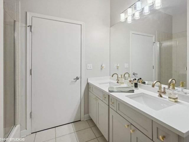 full bathroom with tile patterned flooring, double vanity, tiled shower, and a sink