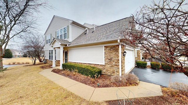 view of home's exterior featuring a shingled roof, stone siding, a lawn, and an attached garage