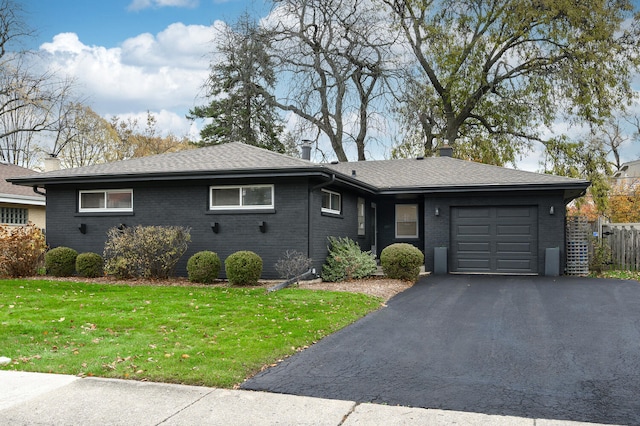 ranch-style house featuring a front lawn, brick siding, an attached garage, and aphalt driveway