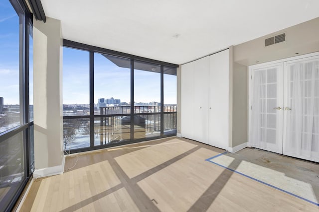 interior space featuring visible vents, a city view, floor to ceiling windows, french doors, and access to outside