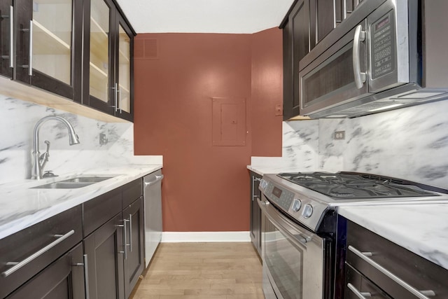 kitchen featuring a sink, decorative backsplash, light wood finished floors, and stainless steel appliances