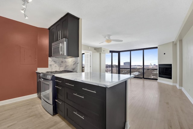 kitchen with tasteful backsplash, dark cabinets, gas range, and expansive windows