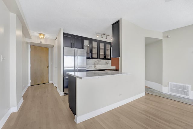 kitchen featuring dark cabinets, visible vents, freestanding refrigerator, and light wood-type flooring