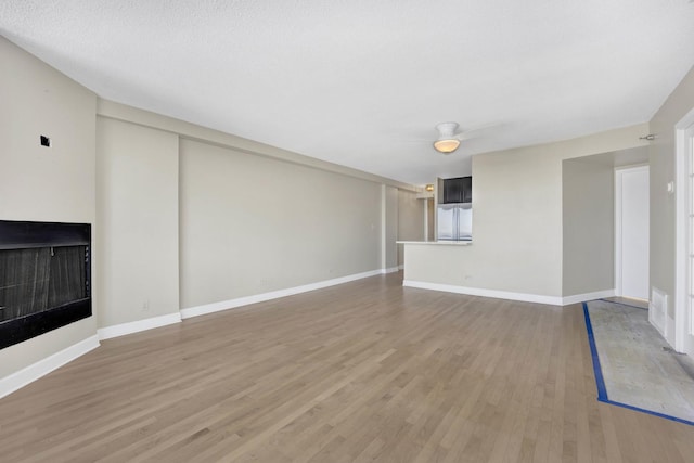 unfurnished living room with light wood-type flooring, baseboards, and a fireplace