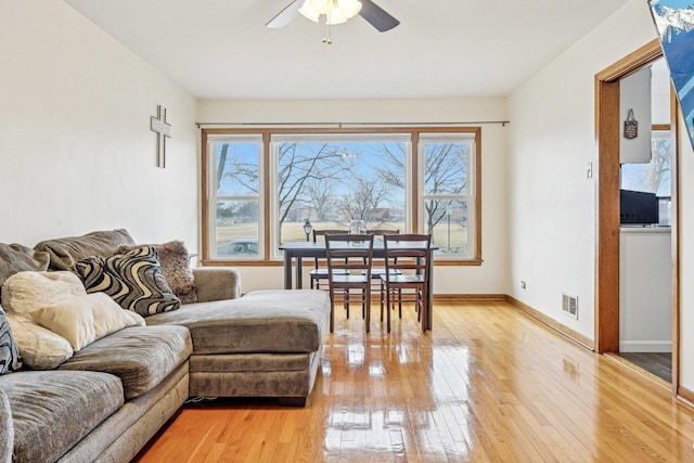 living room featuring baseboards, a healthy amount of sunlight, light wood-style flooring, and a ceiling fan