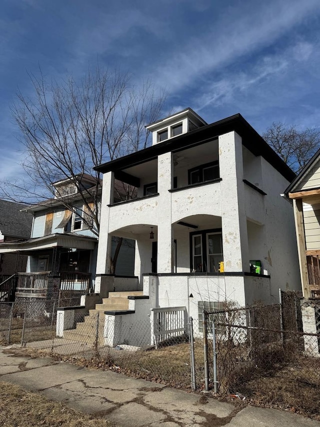 view of front of home featuring a balcony, covered porch, a fenced front yard, and stucco siding