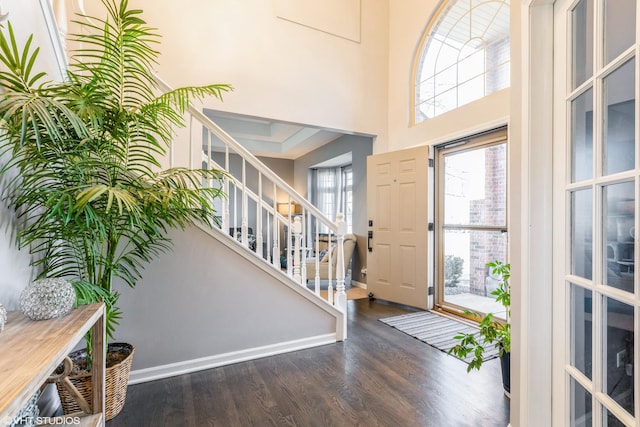 entrance foyer with a towering ceiling, baseboards, wood finished floors, and stairs