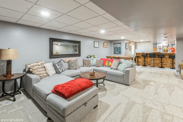 carpeted living area featuring a dry bar and a paneled ceiling