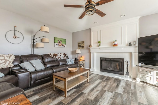 living room featuring ceiling fan, wood finished floors, and a tile fireplace