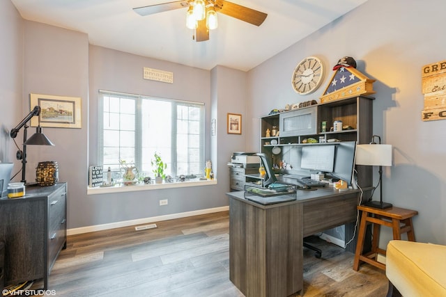 home office featuring visible vents, a ceiling fan, baseboards, and wood finished floors