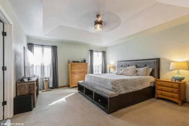 bedroom with carpet flooring, multiple windows, and a tray ceiling