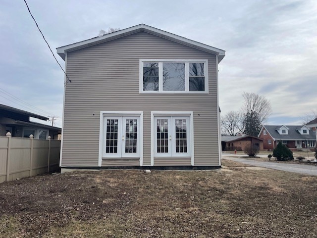 rear view of property with french doors and fence