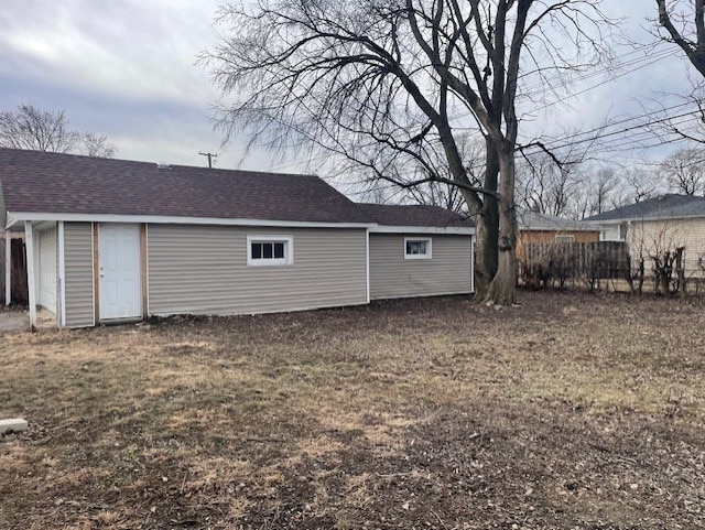 exterior space with a shingled roof and fence