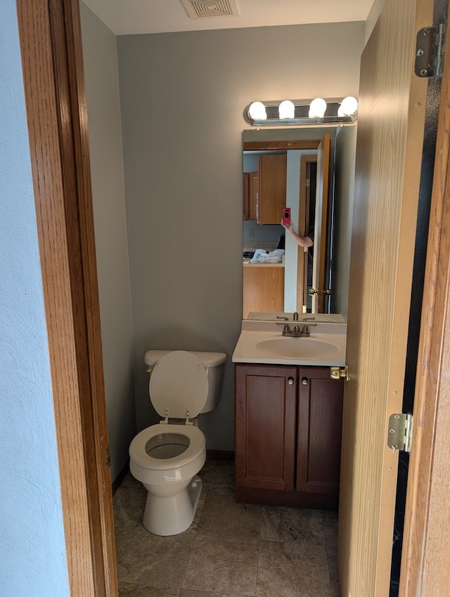 bathroom with toilet, visible vents, baseboards, vanity, and tile patterned floors