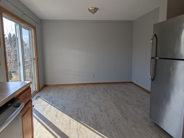 unfurnished dining area with light wood-type flooring and baseboards