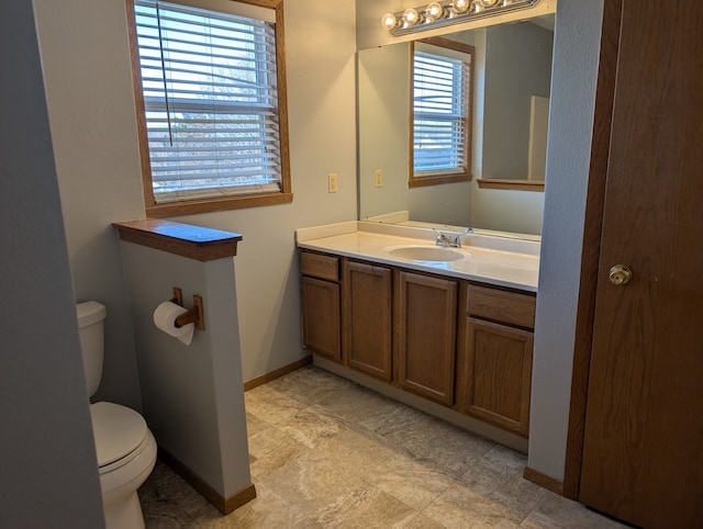 bathroom featuring vanity, toilet, and baseboards