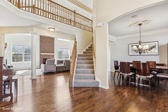 staircase with a fireplace, wood finished floors, crown molding, and a healthy amount of sunlight