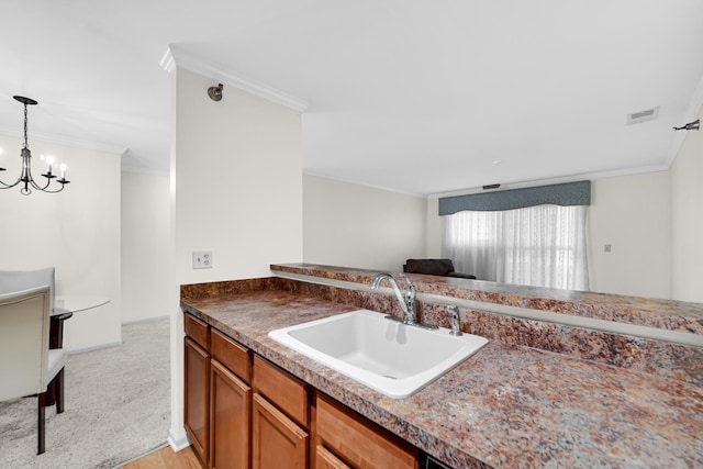 kitchen with visible vents, brown cabinets, ornamental molding, a sink, and an inviting chandelier