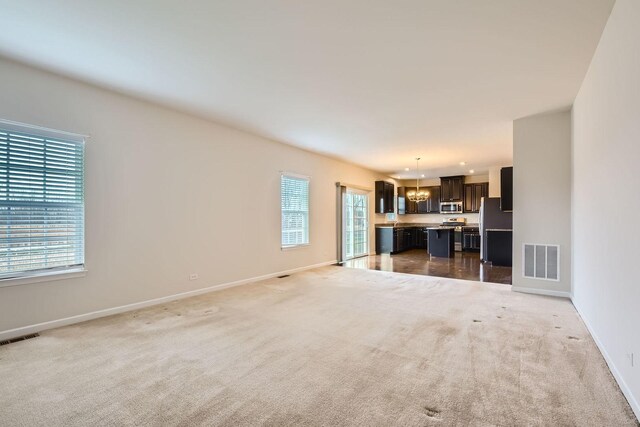 unfurnished living room with baseboards, visible vents, and carpet flooring