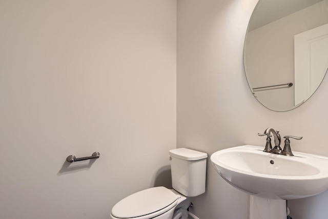 bathroom featuring baseboards, a sink, and toilet