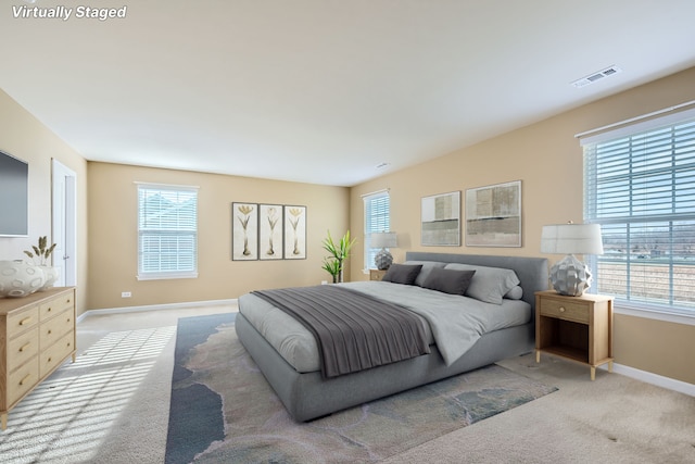 bedroom featuring visible vents, light carpet, and multiple windows