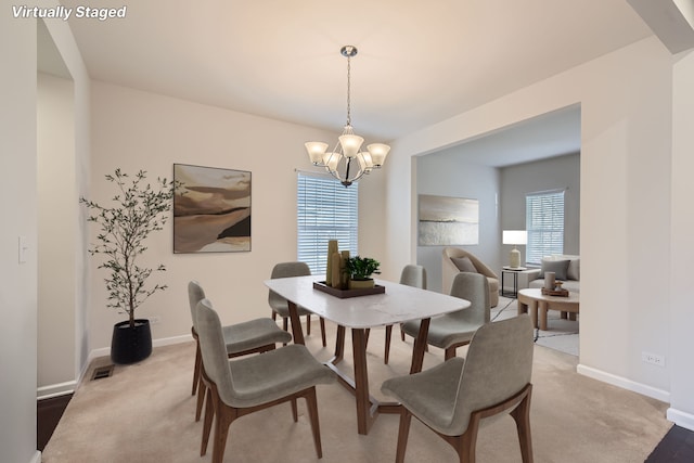 dining area featuring light colored carpet, visible vents, baseboards, and an inviting chandelier