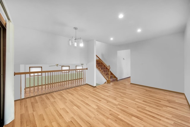 unfurnished room with stairs, ceiling fan with notable chandelier, wood finished floors, and recessed lighting