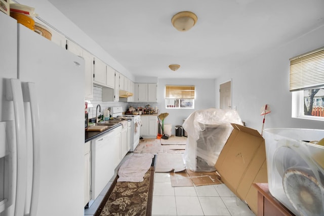 kitchen with white appliances, tasteful backsplash, light tile patterned floors, white cabinetry, and a sink