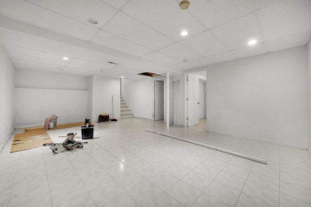 finished basement with tile patterned flooring, stairs, a drop ceiling, and recessed lighting