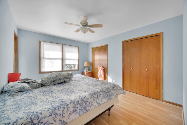 bedroom with light wood-style floors, baseboards, ceiling fan, and multiple closets