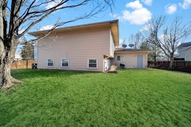 rear view of property featuring fence and a lawn