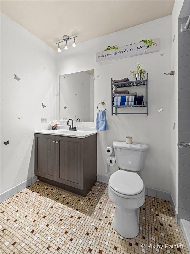 bathroom with toilet, tile patterned flooring, baseboards, and vanity