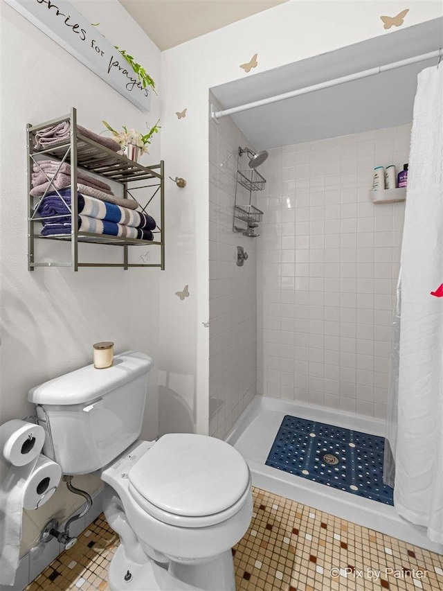 full bath with a stall shower, tile patterned flooring, and toilet