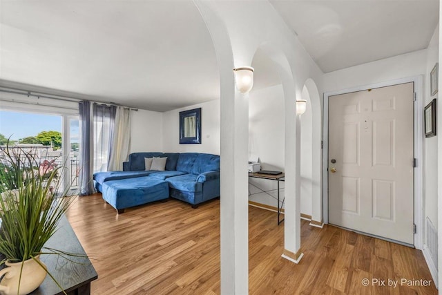 entrance foyer featuring light wood-style floors, baseboards, and arched walkways