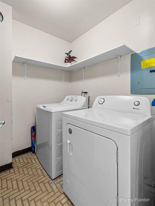 clothes washing area featuring laundry area, electric panel, brick floor, and washer and dryer