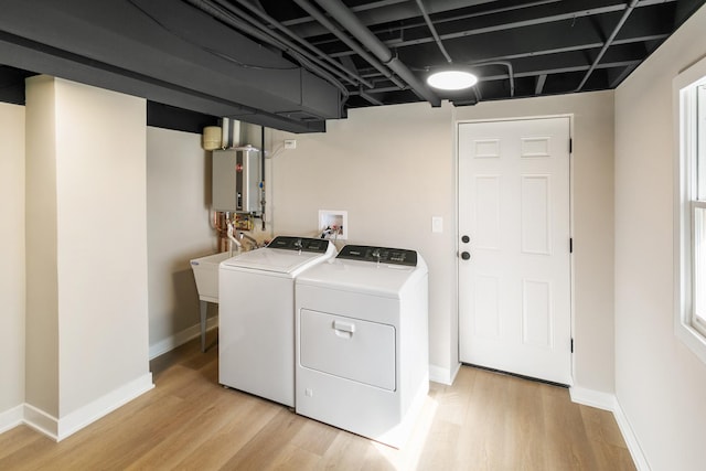 washroom with water heater, independent washer and dryer, light wood-style flooring, and baseboards