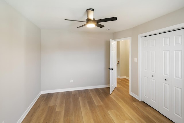 unfurnished bedroom with ceiling fan, a closet, light wood-style flooring, and baseboards