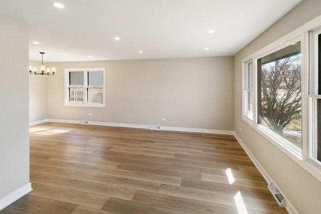 spare room with a chandelier, recessed lighting, light wood-style flooring, and baseboards