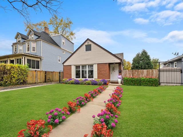 view of front of home featuring brick siding, fence, and a front lawn