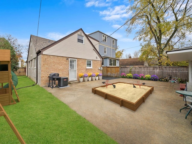 rear view of house featuring a playground, a fenced backyard, brick siding, a yard, and a patio area