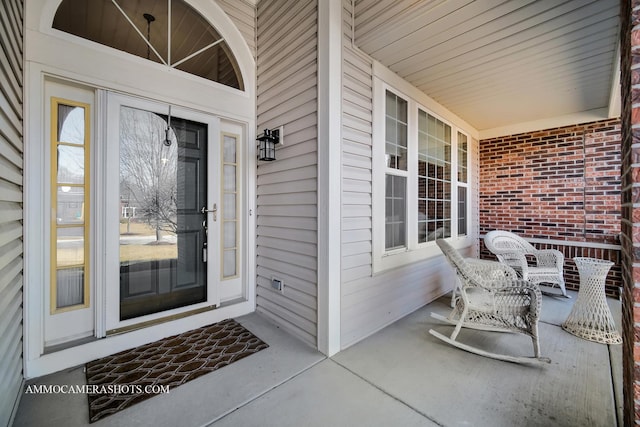 doorway to property featuring brick siding and covered porch