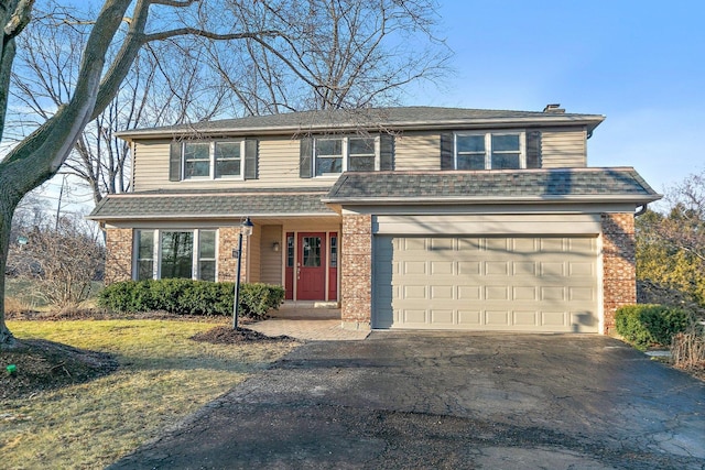 traditional home featuring brick siding, roof with shingles, a chimney, a garage, and driveway