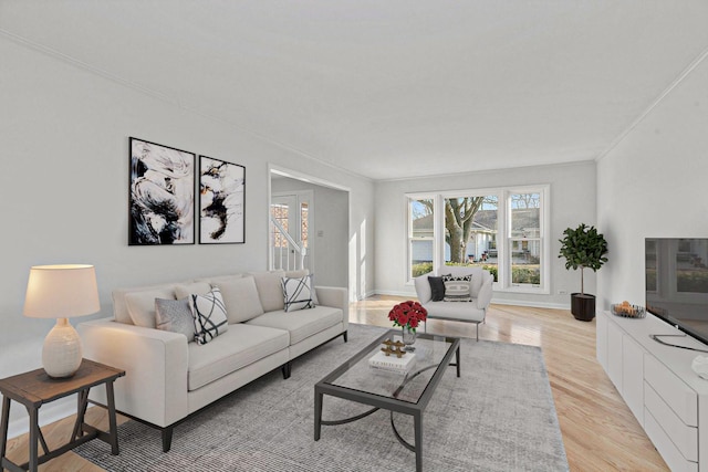 living room with light wood-type flooring, baseboards, and crown molding