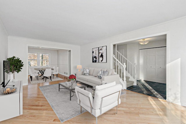 living area with wood finished floors, crown molding, baseboards, and stairs