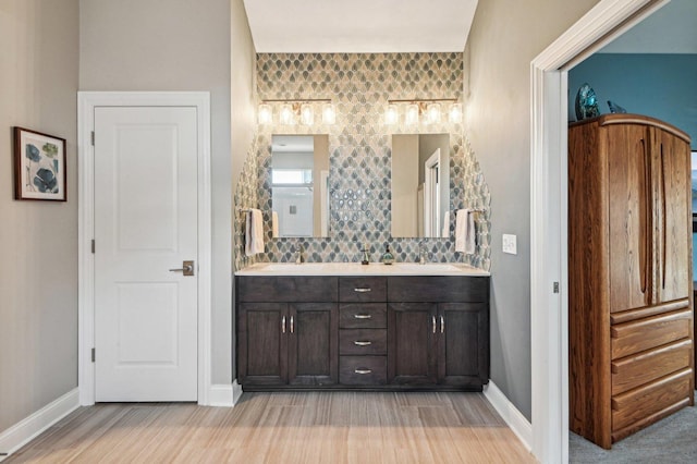 full bath featuring double vanity, wood finished floors, and baseboards