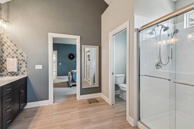 bathroom featuring baseboards, toilet, vanity, and a shower stall