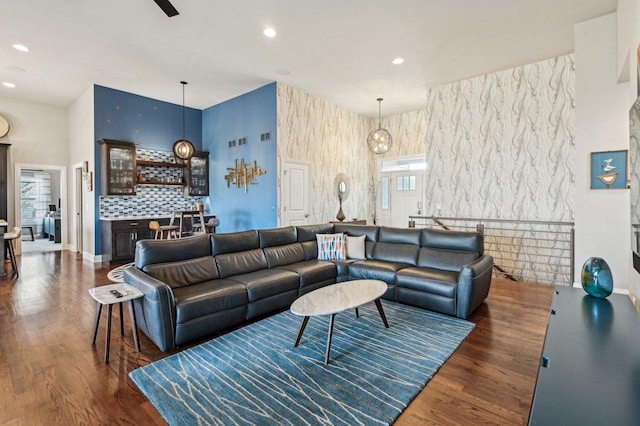 living area featuring a bar, recessed lighting, dark wood-style flooring, and baseboards