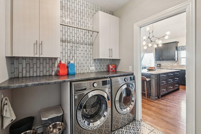 laundry room featuring cabinet space, independent washer and dryer, wood finished floors, and an inviting chandelier