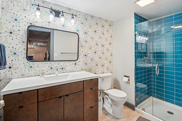 full bath featuring toilet, a stall shower, vanity, and wallpapered walls