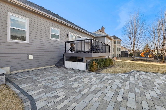 exterior space with a wooden deck, a playground, a trampoline, and fence